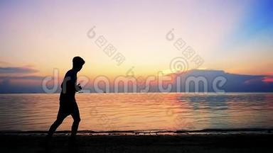 在令人惊叹的日落时分，年轻男子的剪影正在热带海滩上奔跑。 慢动作。 1920x1080